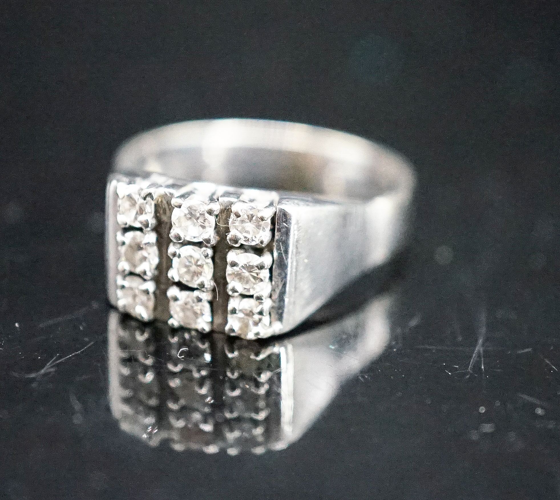 A 750 white metal and nine stone diamond set tablet ring, size S/T, gross 7.6 grams.